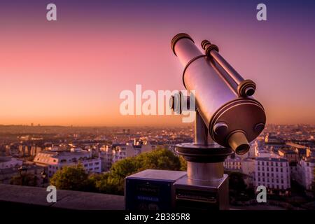 Vue sur Paris depuis Montmartre Hill avec un lever de soleil doré et une lumière rose et pourpre reflétant le télescope art déco. Banque D'Images