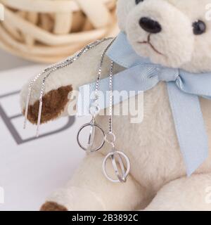 Une paire de magnifiques boucles d'oreilles en argent 925 s'affichent sur un ours en peluche Banque D'Images