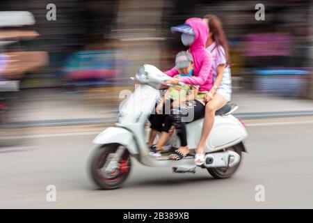 Motion photo brouillée de la population locale, des femmes et un enfant, portant des masques, scooter de conduite dans les rues de Hanoi, Vietnam, 3 avril 2018 Banque D'Images