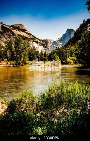 Image en couleur de la vallée en forme de U et du demi-dôme du parc Yosemite avec rivière qui traverse la vallée Banque D'Images