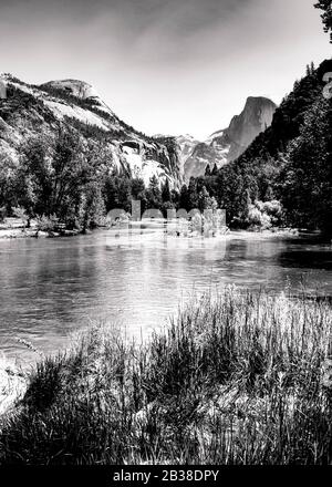 Image en noir et blanc de la vallée en forme de U et du demi-dôme du parc Yosemite avec rivière qui traverse la vallée Banque D'Images