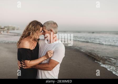 Vue latérale d'un couple marié qui s'embrasse l'un l'autre dans l'océan Banque D'Images