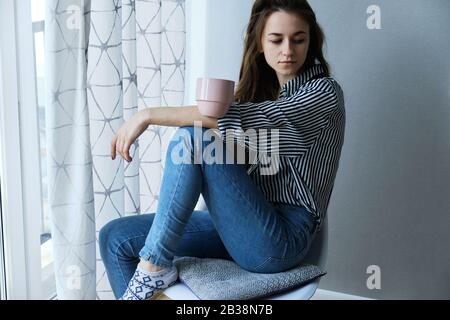 fille à poil brun millénaire qui boit du thé avec des gâteaux seuls Banque D'Images