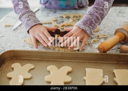 Les mains de jeunes filles utilisent un emporte-pièce sur la pâte à biscuits Banque D'Images