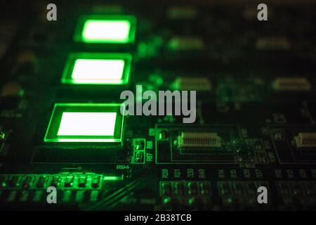 Processus de vérification de plusieurs écrans oled sur la station de test. Affiche un gros plan lumineux de couleur verte. Banque D'Images