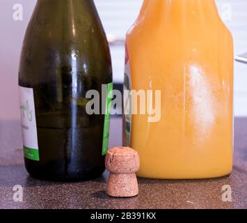 Une bouteille de champagne et une bouteille de jus d'orange sur une table avec un liège. Banque D'Images