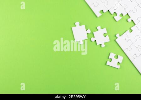vue de dessus d'un puzzle blanc vierge inachevé sur fond vert, en réalisant une tâche ou en résolvant un concept de problème Banque D'Images