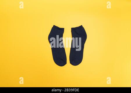 Chaussettes noires sur fond jaune, vue de dessus. Composition minimale Banque D'Images