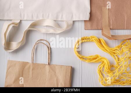 Sac à provisions, sac en maille jaune et sacs en papier pour produits sur fond blanc, concept zéro déchet Banque D'Images
