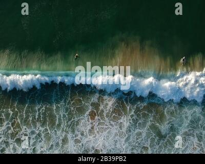 Vue de drone de belles vagues turquiose de mer se brisant sur le littoral sablonneux. Photo aérienne de la plage dorée à la rencontre de l'eau de l'océan bleu profond et des vagues mousseuse Banque D'Images