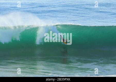 Le surfeur du Bodyboard fait une vague au coucher du soleil. Banque D'Images