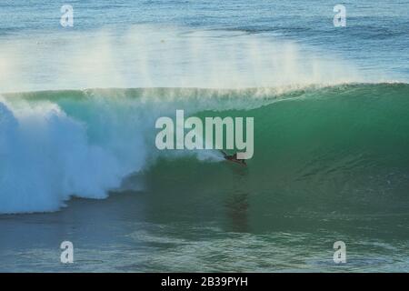 Le surfeur du Bodyboard fait une vague au coucher du soleil. Banque D'Images