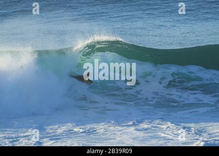 Le surfeur du Bodyboard fait une vague au coucher du soleil. Banque D'Images