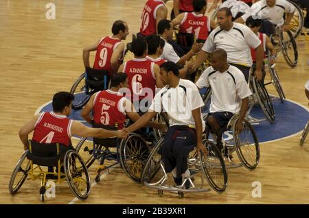 Athènes, Grèce 26 septembre 2004 : compétition paralympique entre le Brésil (blanc) et l'Iran (rouge) en basket-ball en fauteuil roulant pour hommes, avec des membres de l'équipe qui se secouent la main avec des adversaires après le match.©Bob Daemmrich Banque D'Images