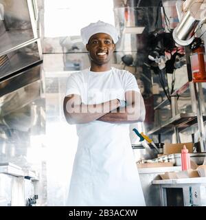 chef positif africain américain debout avec des bras croisés dans le camion alimentaire Banque D'Images