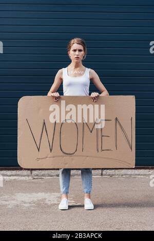 vue sur toute la longueur du placarde féministe tenant avec des femmes de mot dans la rue Banque D'Images