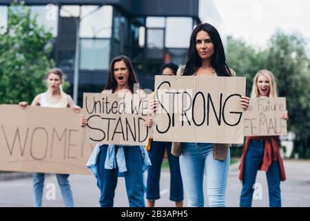 hurler les féministes en tenant des pancartes avec des slogans dans la rue Banque D'Images