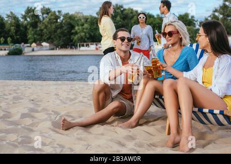 de jeunes amis multiculturels parlent et boivent de la bière tout en s'amusant sur la plage Banque D'Images
