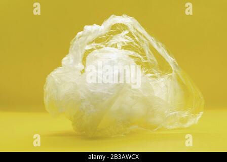 Sac en plastique transparent blanc écrasé en polyéthylène transparent sur fond jaune Banque D'Images