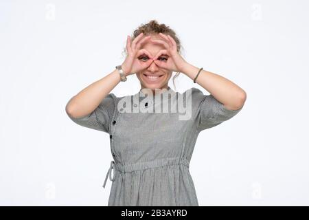 Jolie fille tenant les doigts près des yeux comme des lunettes comme elle a besoin d'acheter de nouveaux verres. Masque de super héros ou chouette Banque D'Images