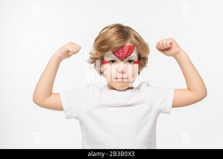 adorable garçon avec masque de spiderman peint sur le visage montrant la puissance isolée sur blanc Banque D'Images