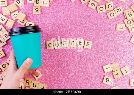 Tasse de café en papier bleu simple à motif plat à la main, le mot café et beaucoup de lettres en bois sur un fond rose brillant et coloré à la mode. Banque D'Images