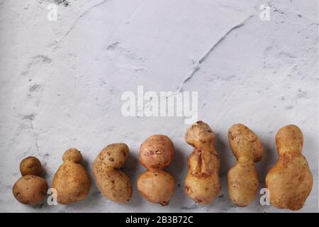 Pommes de terre anormales biologiques laides sur fond de marbre, concept légumes biologiques Banque D'Images