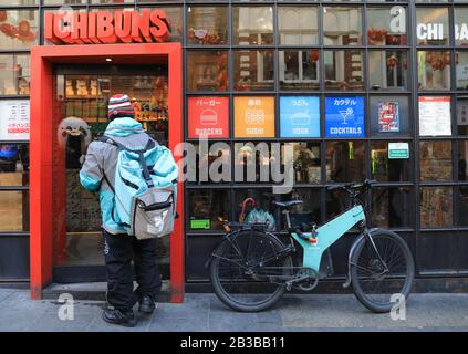 Le cycliste Deliveroo prend livraison sur Wardour Street, dans le quartier chinois de Londres, au Royaume-Uni Banque D'Images