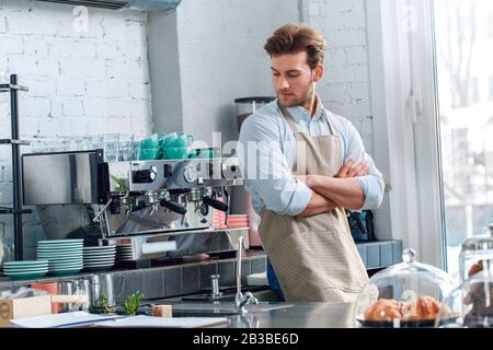 Jeune barista adulte travaillant dans un café en regardant une machine à café Banque D'Images