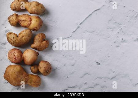 Pommes de terre anormales biologiques laides sur fond de marbre, concept légumes biologiques Banque D'Images