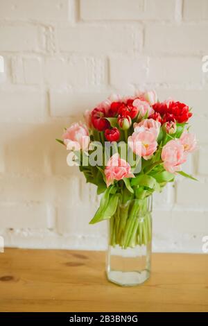 Vase en verre avec bouquet de magnifiques tulipes sur fond de mur de briques Banque D'Images