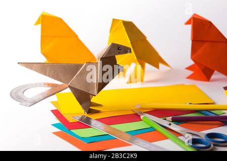 oiseau origami et dinosaure en papier de couleur. papier, règle, crayons, couteau. passe-temps intéressant Banque D'Images
