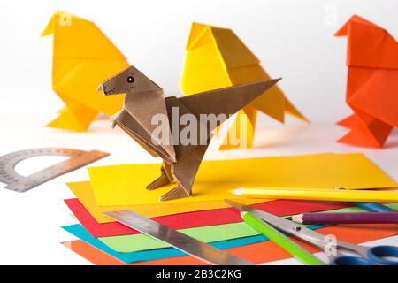 oiseau origami et dinosaure en papier de couleur. papier, règle, crayons, couteau. passe-temps intéressant Banque D'Images