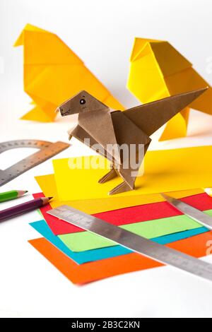 oiseau origami et dinosaure en papier de couleur. papier, règle, crayons, couteau. passe-temps intéressant Banque D'Images