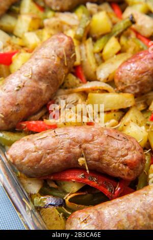 Cuisson des oignons de saucisse et des poivrons rouges et verts dans un plat de cuisine Banque D'Images