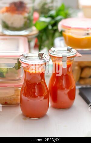 Vue détaillée d'un couple de bocaux de sauce tomate. Les deux couvercles en métal sur eux. Dans le dos de la scène il y a quelques pots de verre plein de homem sain Banque D'Images