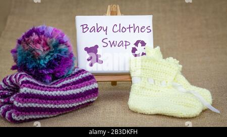 Vêtements pour bébés Échangez de signe et de vêtements pour bébés sur fond de toile de fond, réutilisez, recyclez les vêtements et les textiles pour bébés et enfants, concept de mode durable. Banque D'Images