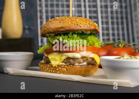 Hamburger gros plan, frites et support de sauce à côté, grille du gril derrière Banque D'Images