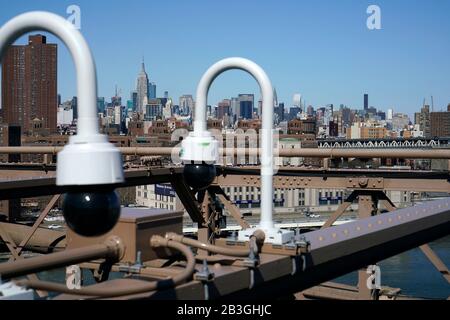 Caméras de sécurité installées sur le pont de Brooklyn avec l'horizon de Manhattan et de l'Empire State Building en arrière-plan, New York City.USA Banque D'Images