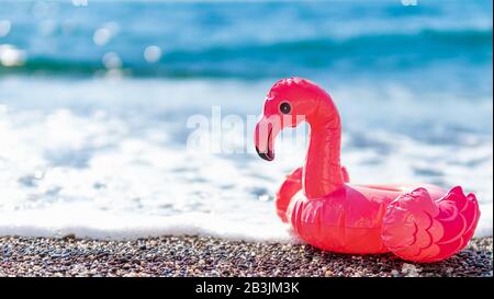 Flamants roses gonflables sur la plage avec mousse blanche de vague de mer. Été, vacances, natation, concept de station balnéaire avec flamango rose. Bannière. Espace de copie pour le texte ou la conception. Banque D'Images