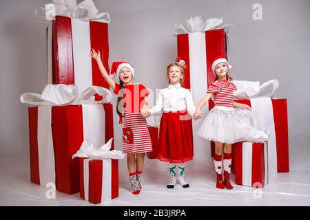 Petites jolies filles en studio avec décoration et accessoires de vacances d'hiver. Les belles filles dans les vêtements de Noël drôle ont des émotions amusantes et animées. Banque D'Images