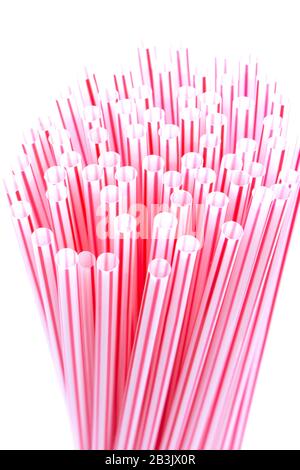Pailles en plastique avec bandes rouges et blanches dans un groupe isolé sur un fond blanc. Concept de déchets plastiques Banque D'Images