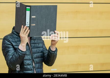 05 mars 2020, Bavière, Würzburg: Un orthophoniste accusé d'abus d'enfants arrive au début du procès dans la salle d'audience de la cour régionale et possède un dossier devant son visage. On dit que les 38 ans ont commis des crimes graves contre des enfants handicapés physiques ou mentaux pour la plupart dans 66 cas. Les victimes présumées auraient entre deux et six ans au moment des attaques. Photo: Daniel Karmann/Dpa Banque D'Images