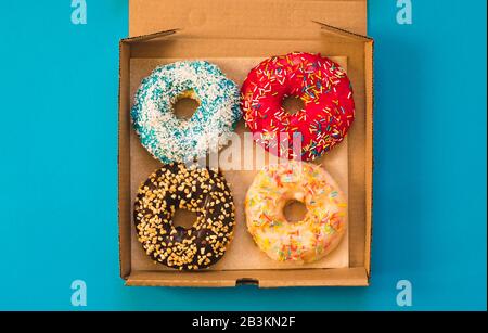 Délicieux beignets sur carton sur fond bleu. Concept de livraison de beignets. Banque D'Images