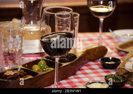 Un verre de vin rouge à une table chargée d'en-cas et d'aliments pour les doigts Banque D'Images