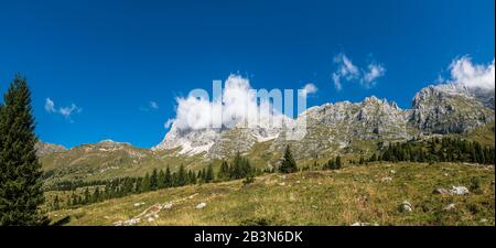 Vue panoramique sur les pics de montagne au-dessus du plateau de Montasio, avec Jof di Montasio partiellement couvert de nuages, en été. Banque D'Images