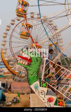 Les Fairgoers attendent qu'une télécabine oscillante commence par deux roues Ferris en arrière-plan, Pushkar Fair, Rajasthan, Inde, Asie Banque D'Images