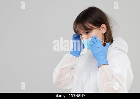 La femme asiatique met sur un masque et un costume de protection. Protégé contre la grippe, le virus ebola, la tuberculose. Équipement de protection individuelle contre les ha biologiques Banque D'Images