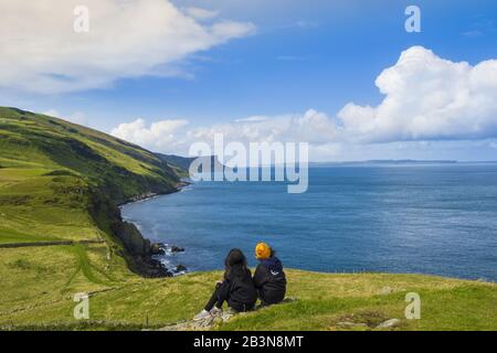 Deux jeunes randonneurs se reposent sur un sentier de randonnée le long de la côte d'Antrim, Ulster, Irlande du Nord, Royaume-Uni, Europe Banque D'Images