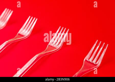 Gros plan de la fourche en plastique transparent sur fond rouge. Motif de vaisselle jetable. Banque D'Images